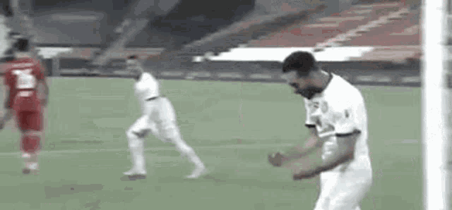 a man is standing on a soccer field in front of a goal while another man runs towards him .