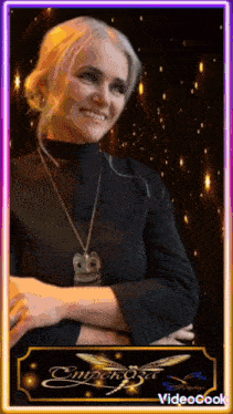 a woman wearing a necklace with an owl on it is smiling in front of a video cook logo