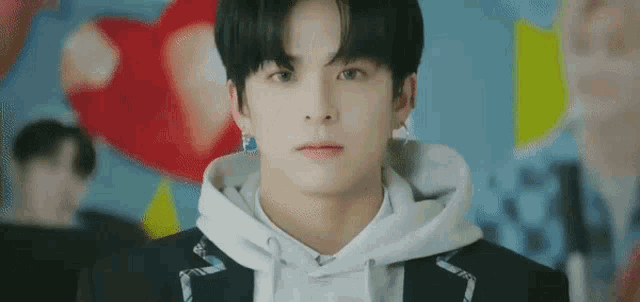 a close up of a young man wearing a hoodie and earrings .