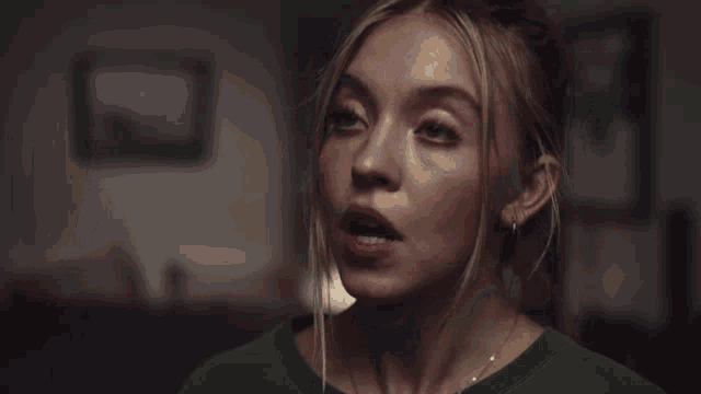 a close up of a woman 's face with a green shirt on