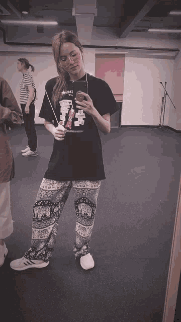 a woman taking a selfie in front of a mirror wearing a black shirt that says ' a ' on it
