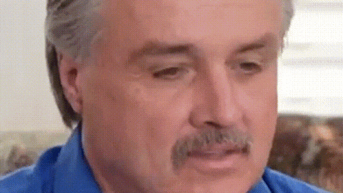 a man with a mustache is wearing a blue shirt .