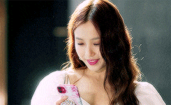 a woman in a white dress is looking at her phone .
