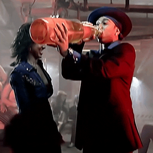 a man in a cowboy hat is drinking from a large barrel