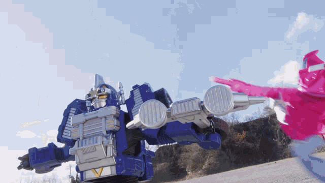 a blue robot with the letter v on it is being kicked by a pink ranger