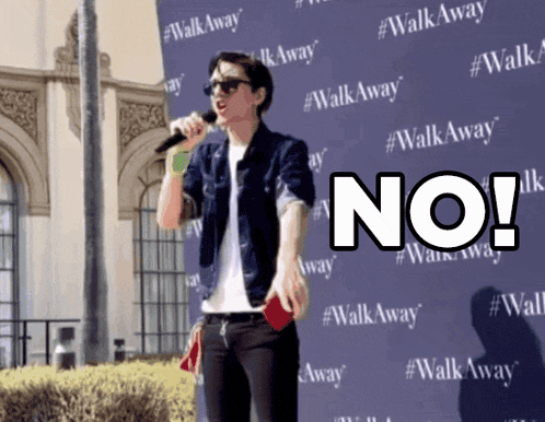a man singing into a microphone in front of a walk away sign