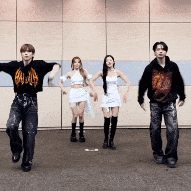 a group of people are dancing in front of a wall and one of them is wearing a hoodie that says pink .
