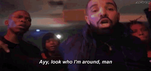 a man with a beard is standing in front of a crowd of people and talking to them .