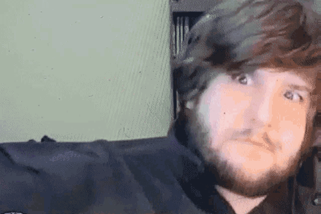 a man with a beard is looking at the camera with a serious look on his face
