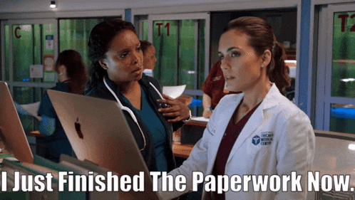two women in lab coats are looking at laptops with the caption i just finished the paperwork now
