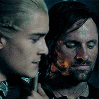 two men are standing next to each other in a dark room .