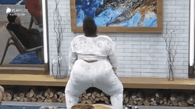 a woman is standing on a yoga mat in front of a painting .
