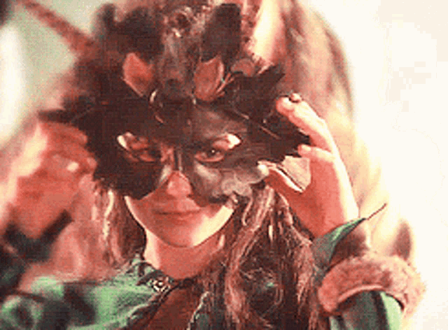a woman wearing a mask with feathers on her head