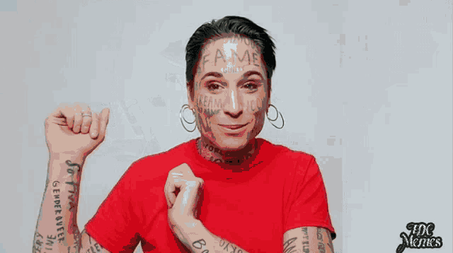 a man in a red shirt has a lot of tattoos on his face