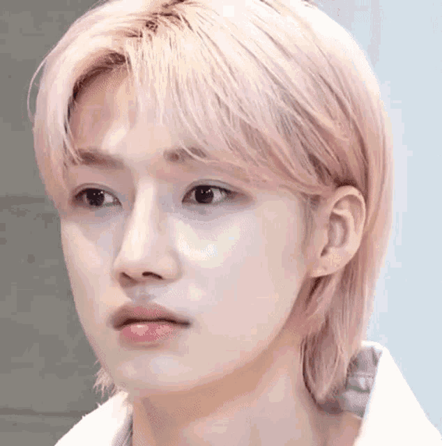 a close up of a person with pink hair and a white shirt .