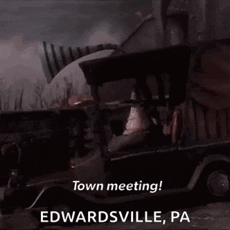 a man is sitting in a car with a horn on top of it and says `` town meeting ! ''