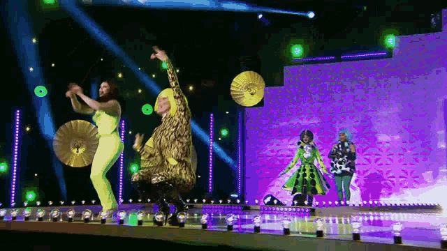 a group of people are dancing on a stage with a purple background .