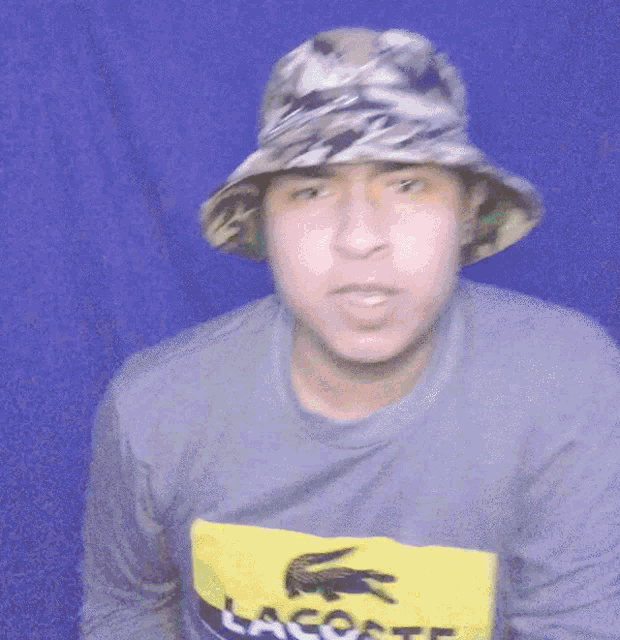 a man wearing a hat and a shirt that says lacoste on it