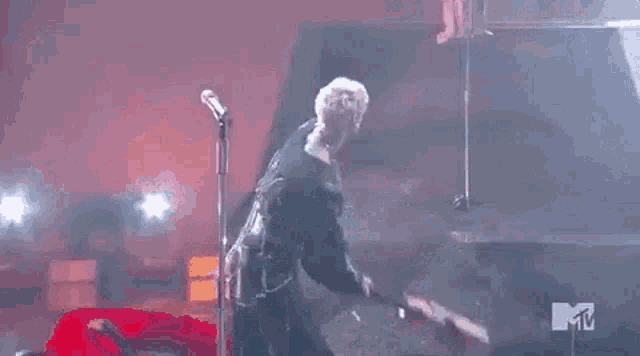 a man is singing into a microphone on stage .