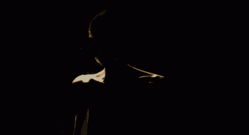 a creepy monster with a smiling face is standing in the dark and looking at the camera .