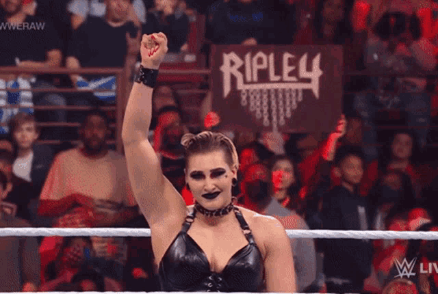 a woman in a wrestling ring holds up her fist in front of a sign that says ripley