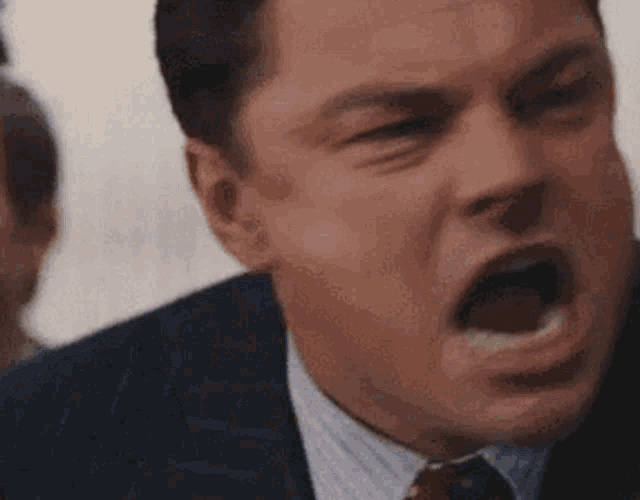 a man in a suit and tie is screaming with his mouth open .