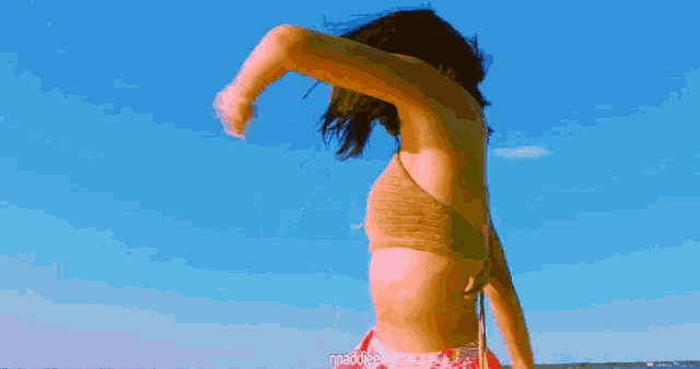 a woman in a bikini is dancing on the beach and the words maddiee are on the bottom right