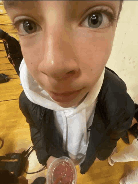 a close up of a person 's face with a cup of juice