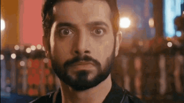 a man with a beard is looking at the camera with a serious look on his face .