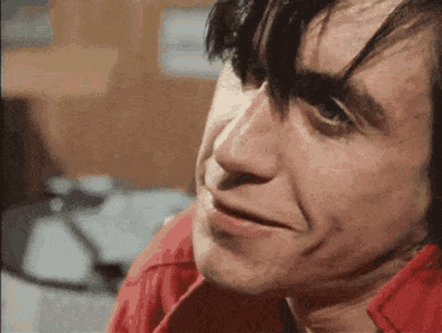 a man in a red shirt is making a funny face .