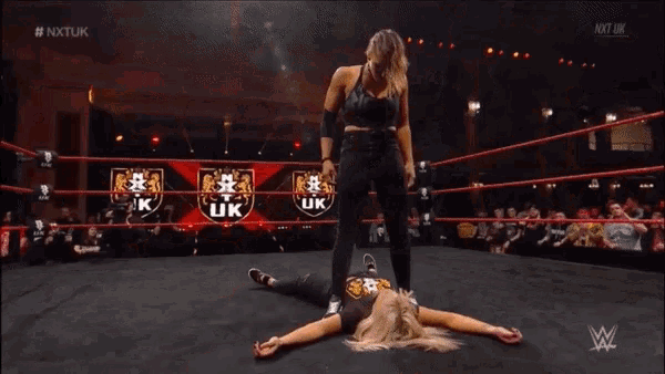 a female wrestler is standing in a ring with a crowd watching