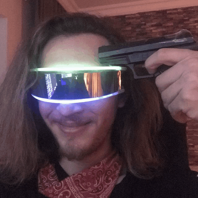 a man wearing futuristic goggles holds a gun