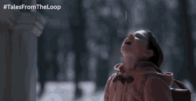 a girl in a pink jacket looks up at the sky with #talesfromtheloop written on the bottom