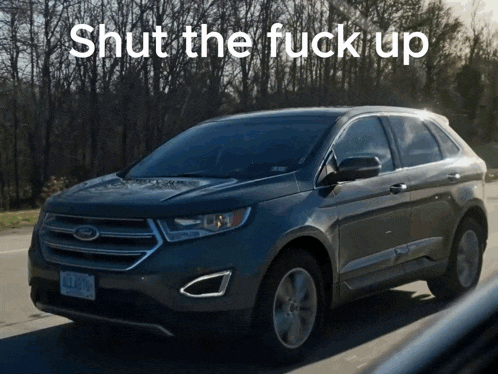 a ford car is driving down the road with the words shut the fuck up written on the bottom