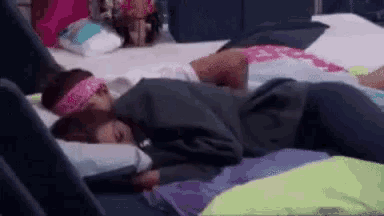 a couple of girls are laying on a bed with their heads on each other .