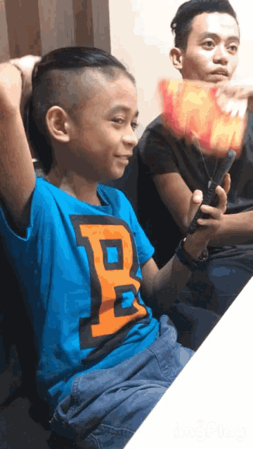 a boy wearing a blue shirt with a letter b on it