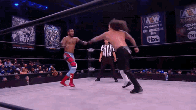 two wrestlers in a wrestling ring with a sign that says aew