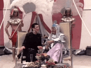 a woman in a pink dress is sitting in a chair talking to a man in a black jacket .