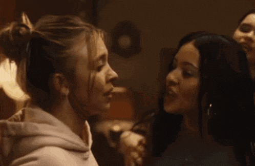 a group of young women are looking at each other and one of them is covering her mouth