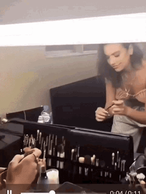 a woman is applying makeup in front of a mirror with the time of 4:04