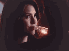 a close up of a woman 's face with a glass in her mouth