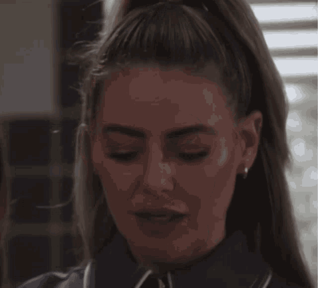a close up of a woman 's face wearing a blue shirt