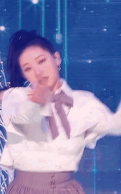 a woman in a white shirt and brown skirt is dancing on a stage .