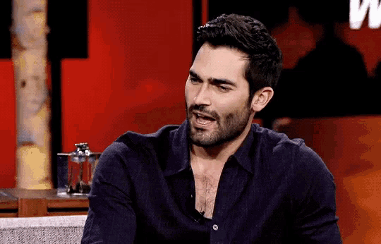 a man with a beard wearing a black shirt is sitting on a chair