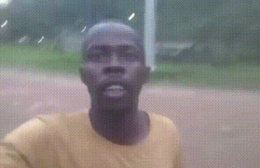 a man in a yellow shirt is taking a selfie with a blurry background .