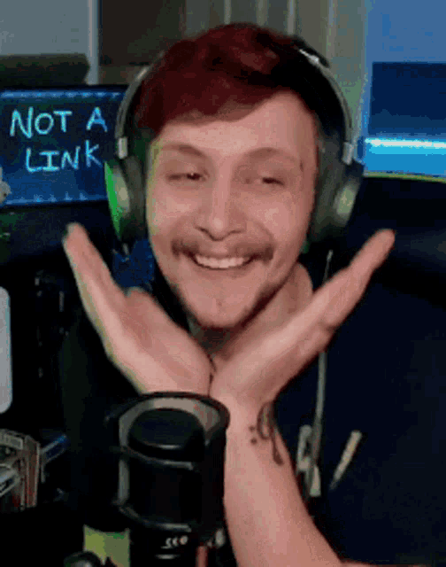 a man wearing headphones is smiling in front of a microphone with a sign that says not a link in the background