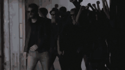 a group of people are standing in a dark room holding their hands up .