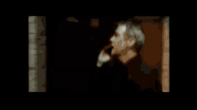 a man talking on a cell phone in front of a brick wall