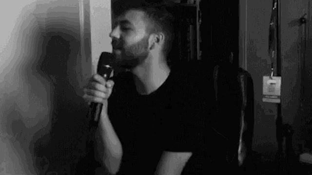 a man is sitting in a chair holding a microphone in his hand .