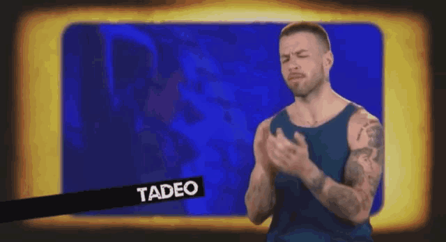 a man in a blue tank top stands in front of a screen with the name tadeo on it